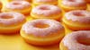 Image features a variety of donuts with a bright lemon yellow frosting.