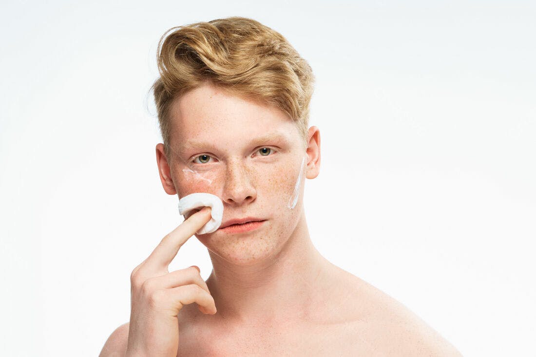 Homem ruivo aplicando creme facial