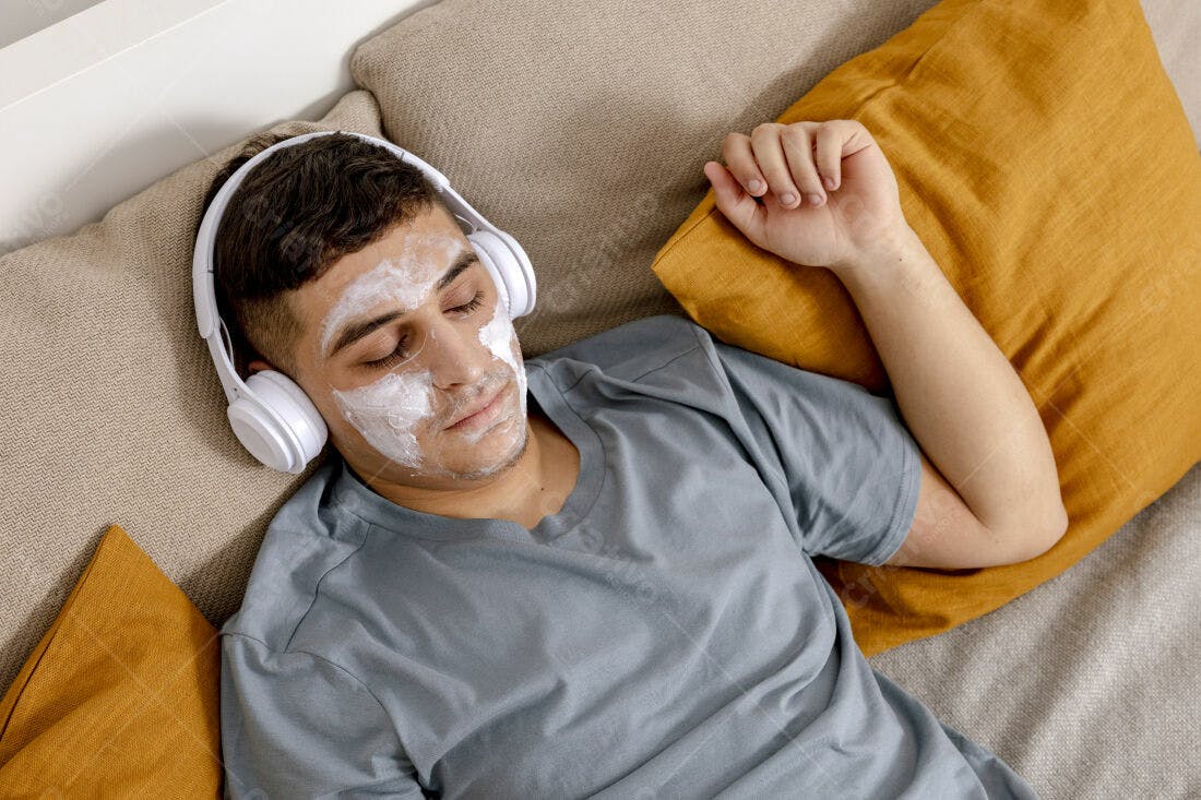 Homem relaxando com máscara facial e fones