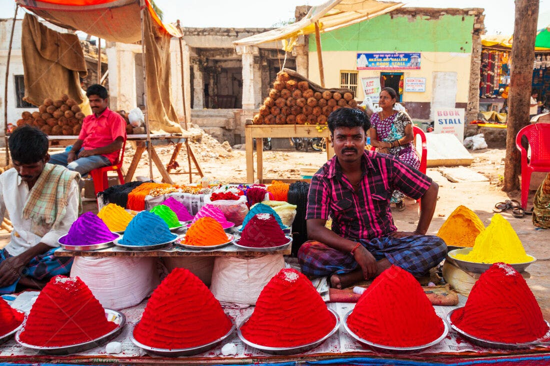 Vendedor indiano com tintas coloridas em mercado