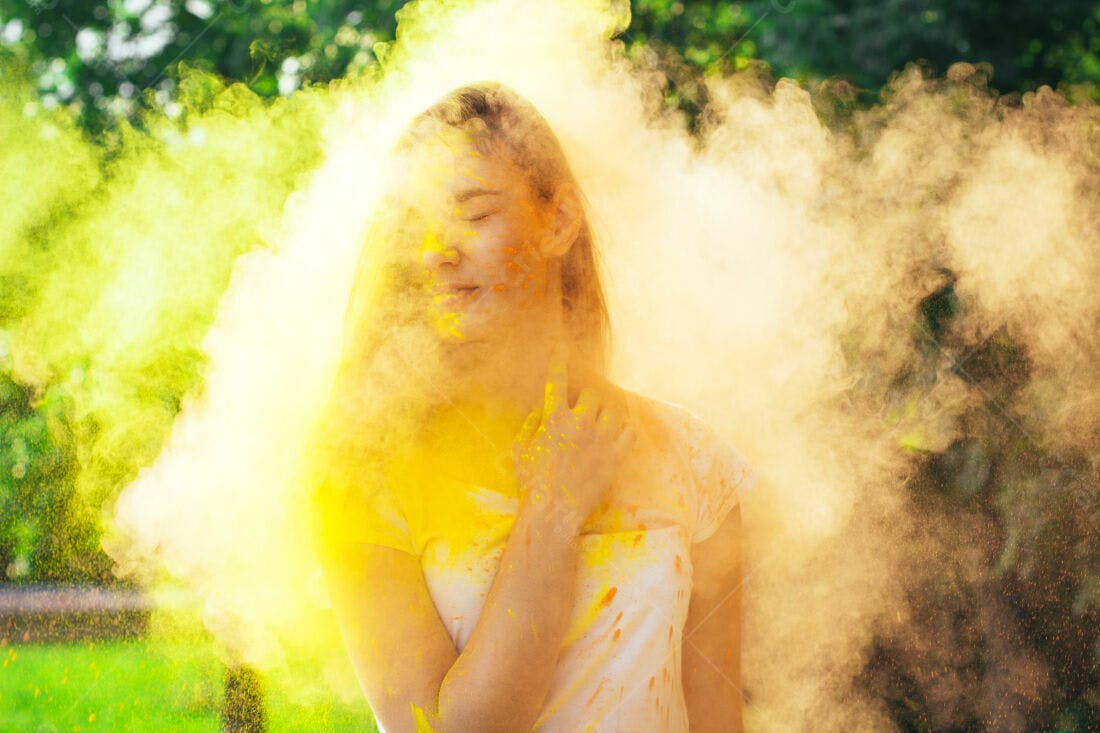 Mulher coberta em pó amarelo Holi