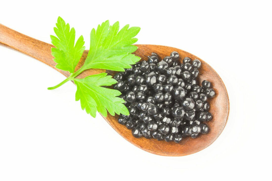 Caviar preto em colher de madeira com salsa
