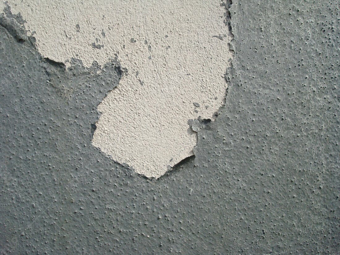 Parede com tinta descascando cinza e bege