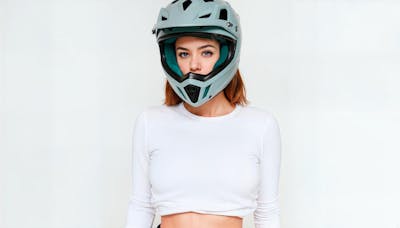 Mulher com capacete de motocross proximo de uma moto off road 