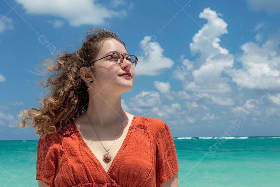 Mulher jovem na praia de vestido laranja