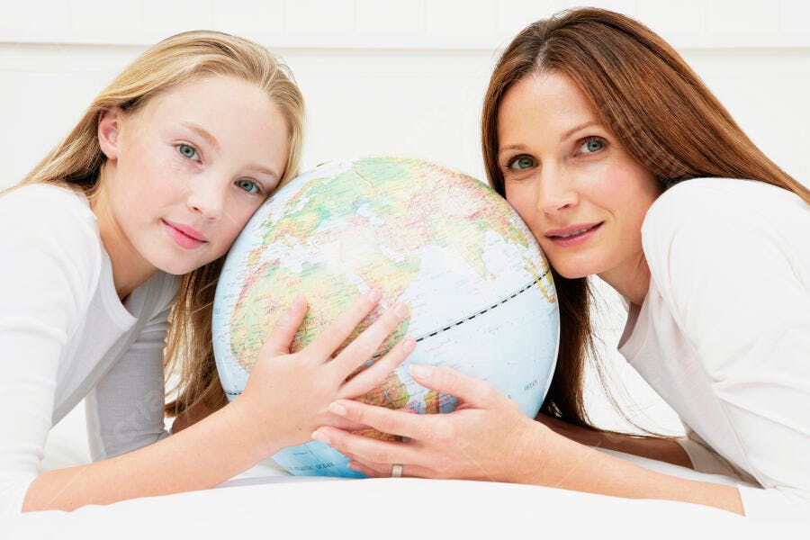 Mãe e filha abraçando um globo terrestre