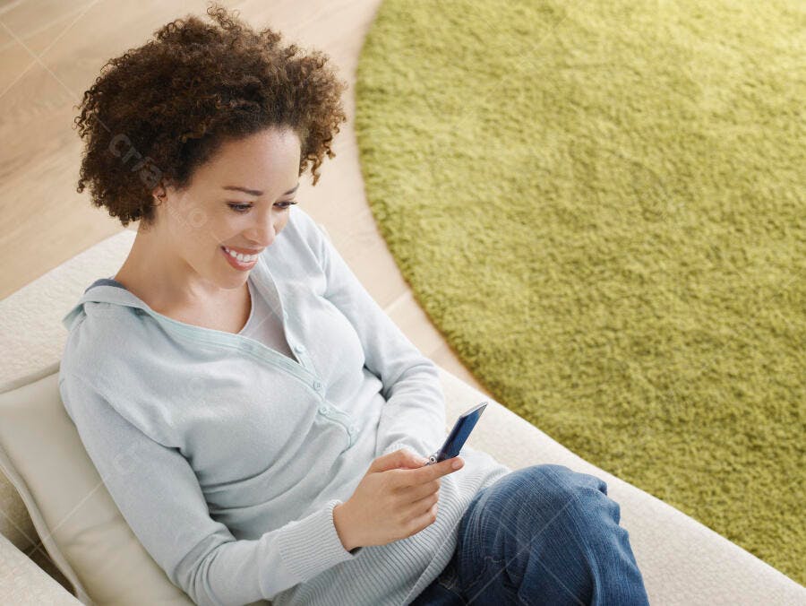 Mulher feliz usando celular em casa