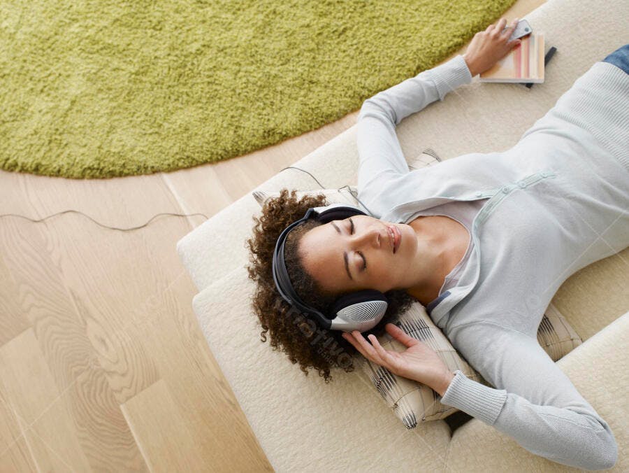 Mulher relaxada ouvindo música no sofá