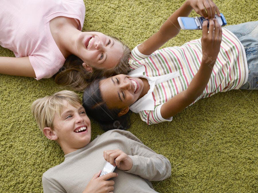 Crianças felizes com celulares em tapete verde