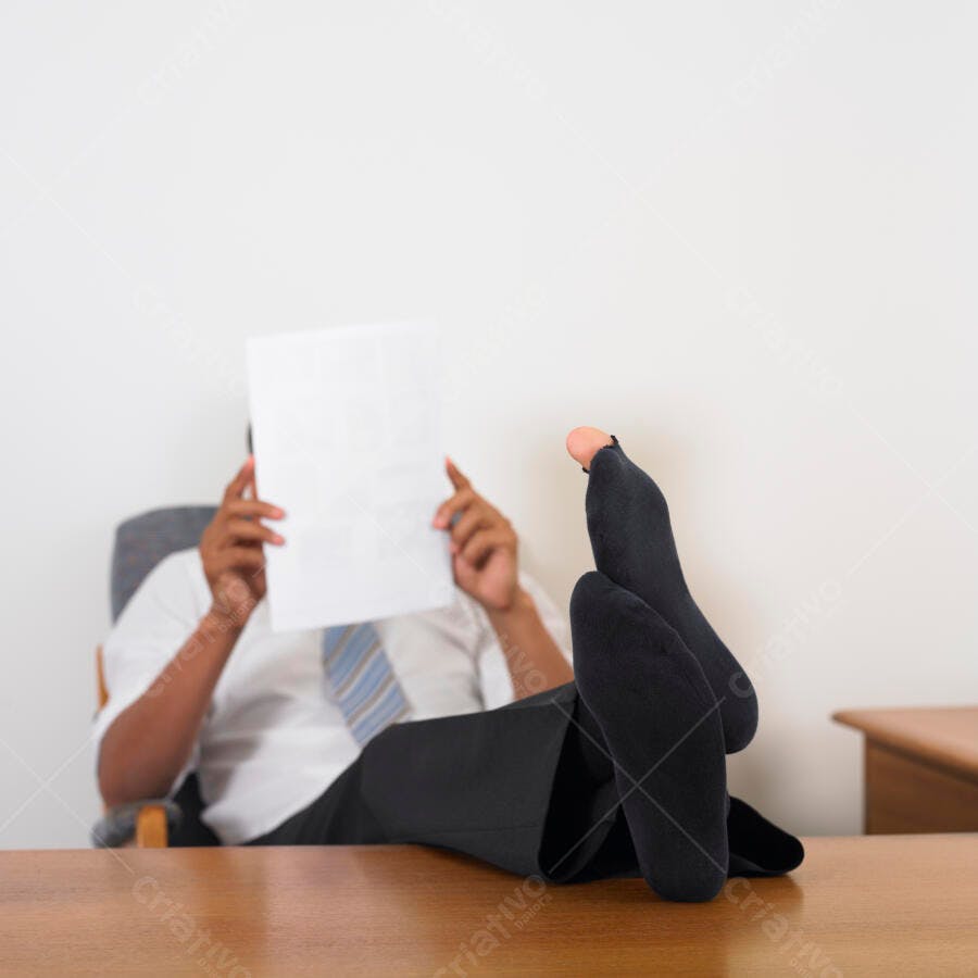 Homem relaxado com os pés na mesa lendo documento