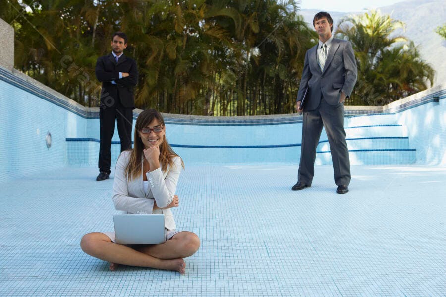 Mulher executiva com laptop na beira de piscina vazia