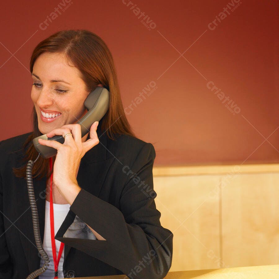 Recepcionista sorridente ao telefone em escritório