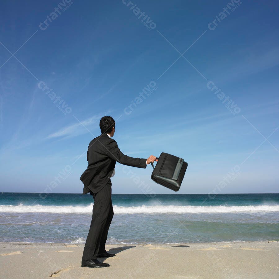 Executivo jogando maleta na praia sob céu azul