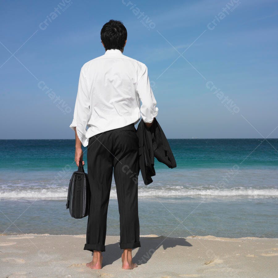Homem de negócios na praia contemplando o mar