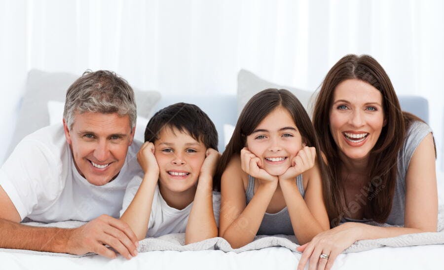 Família feliz deitada na cama sorrindo
