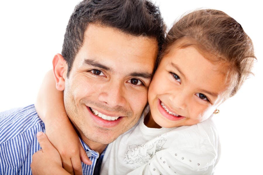 Pai e filha sorrindo abraçados fundo branco