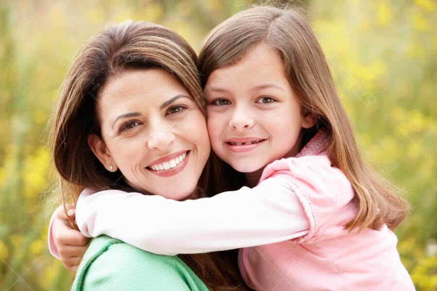 Mãe e filha abraçadas num jardim ensolarado