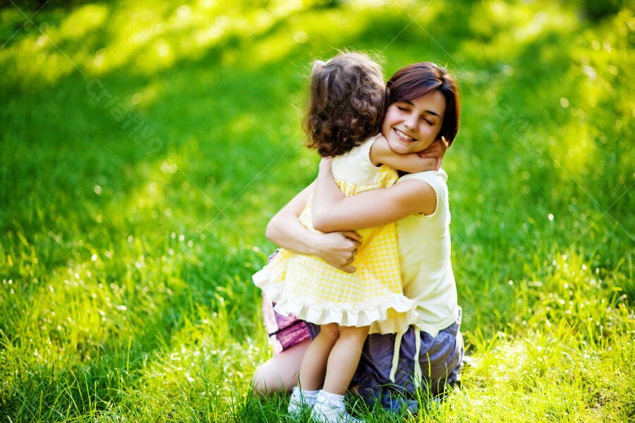 Mãe e filha se abraçando em um gramado