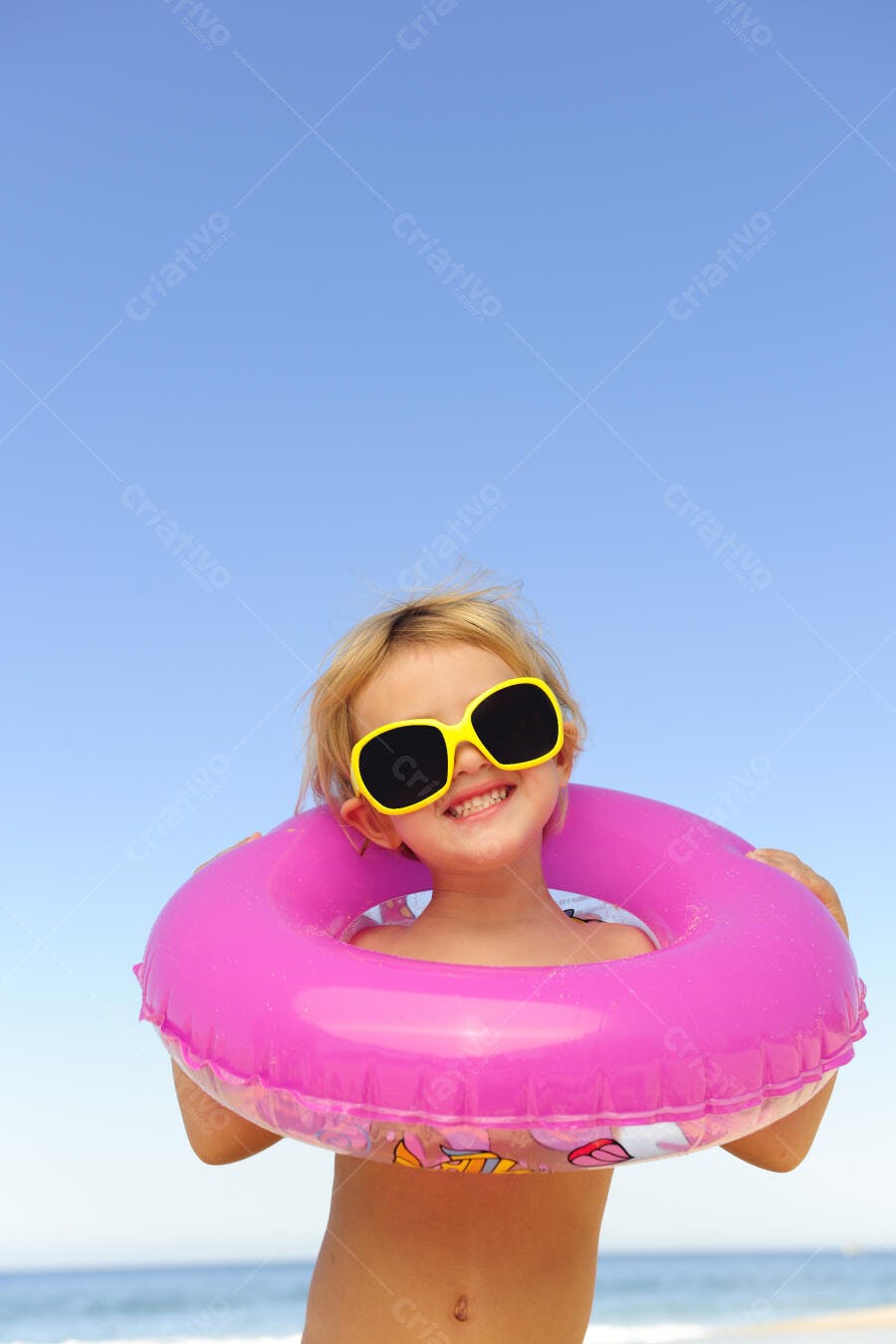 Criança feliz com bóia rosa na praia