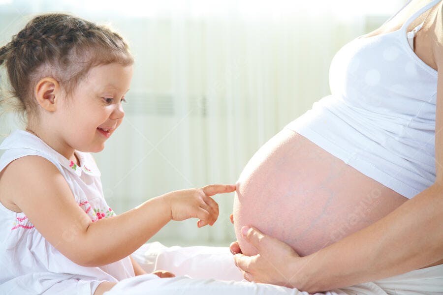 Criança tocando barriga grávida