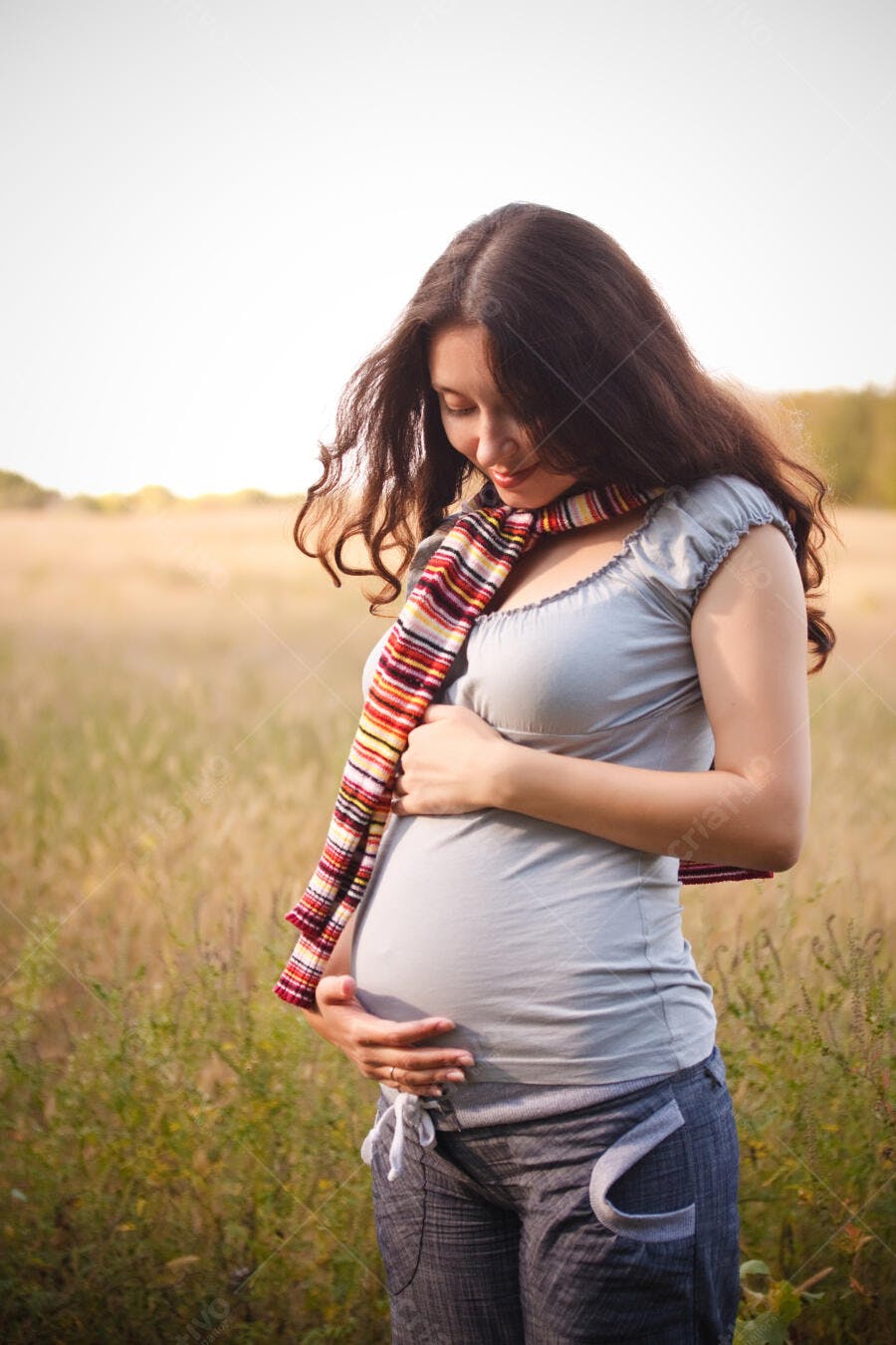 Mulher grávida acariciando a barriga em campo