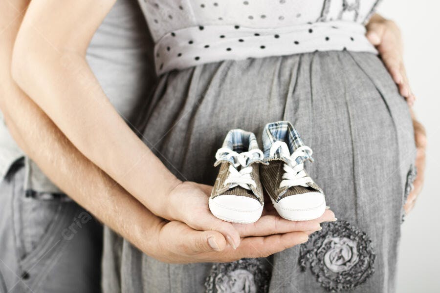 Par de sapatinhos bebê na barriga da mãe