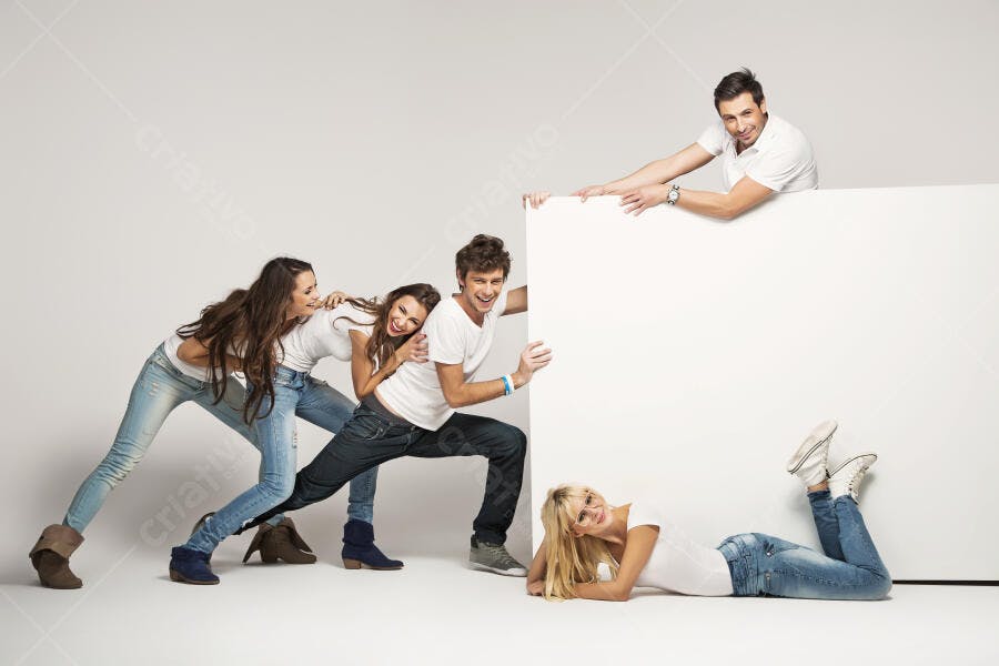 Grupo de amigos jovens e alegres segurando um painel branco