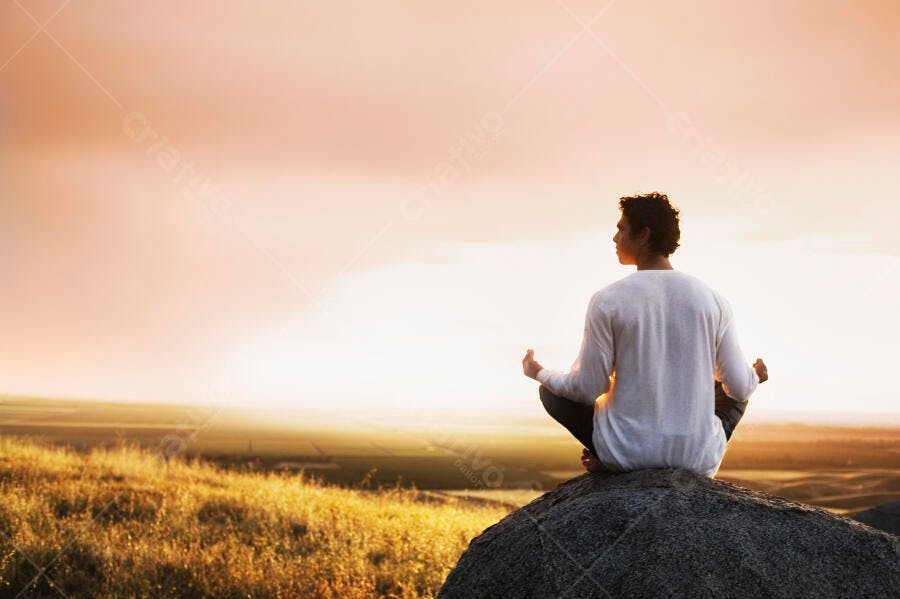 Homem meditando ao pôr do sol