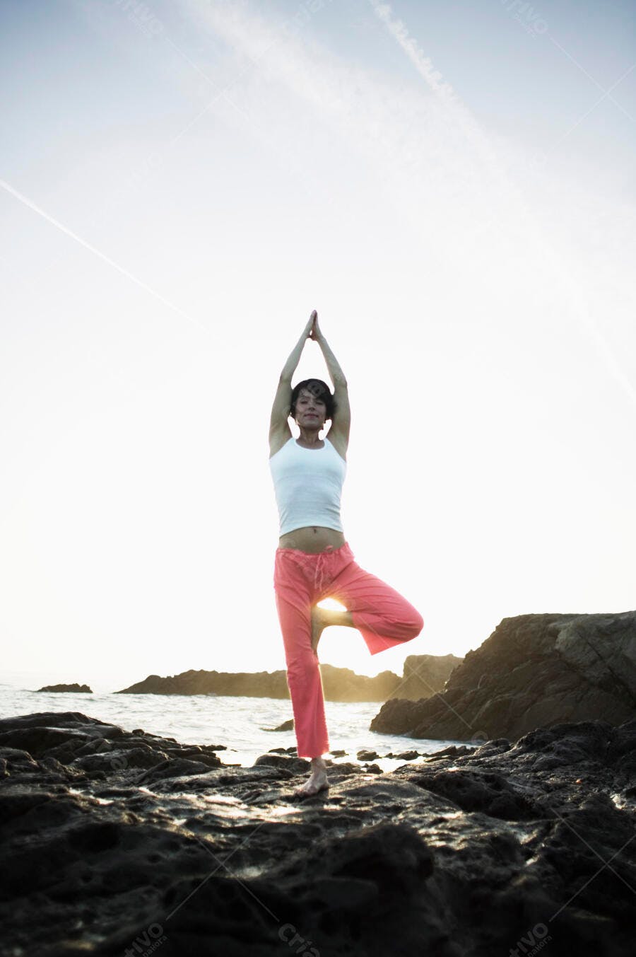 Mulher praticando yoga na praia ao entardecer