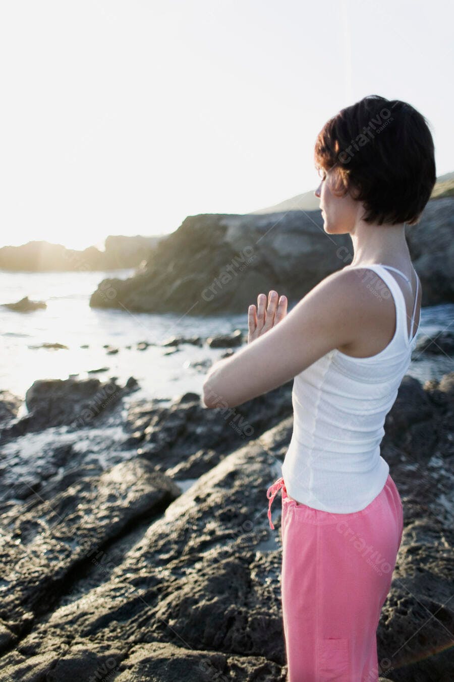 Mulher meditando na praia ao entardecer