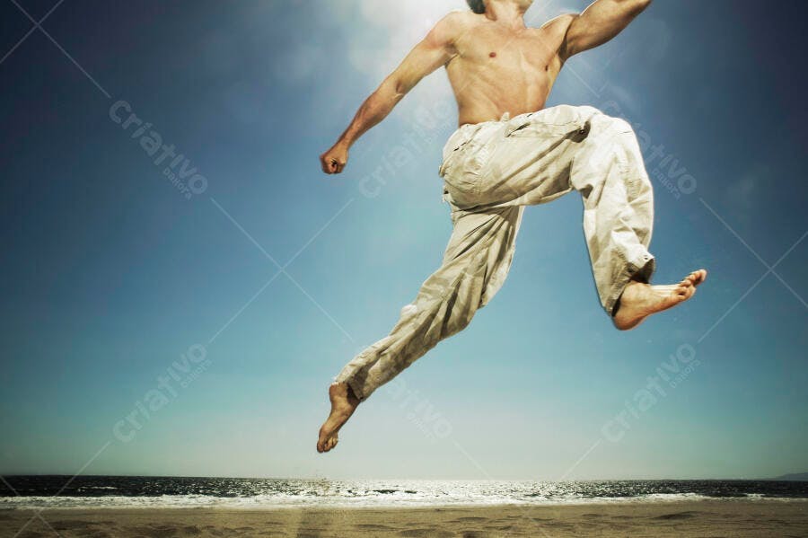Homem saltando na praia dia ensolarado