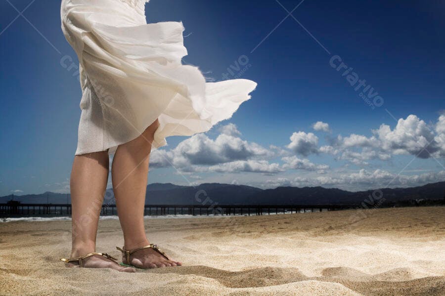 Mulher na praia vestido branco ventoso