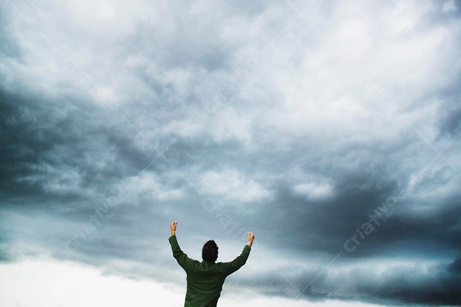 Homem celebrando sob céu nublado