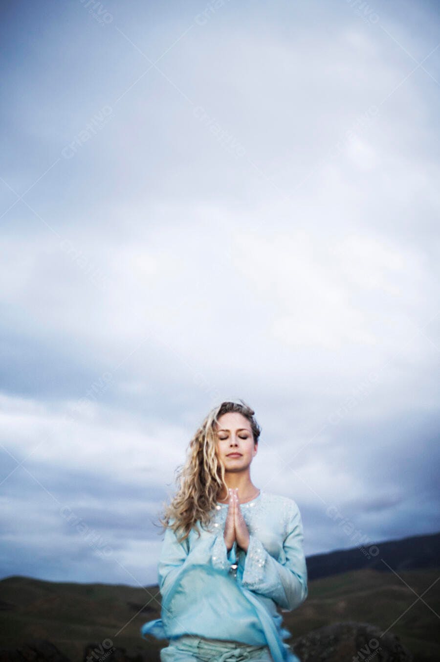 Mulher meditando ao ar livre sob céu nublado