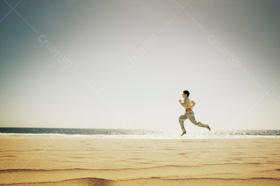 Homem correndo na praia arenosa