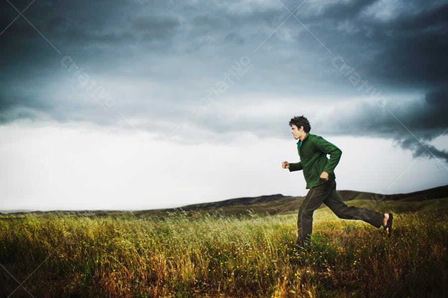 Homem correndo em campo sob céu tempestuoso