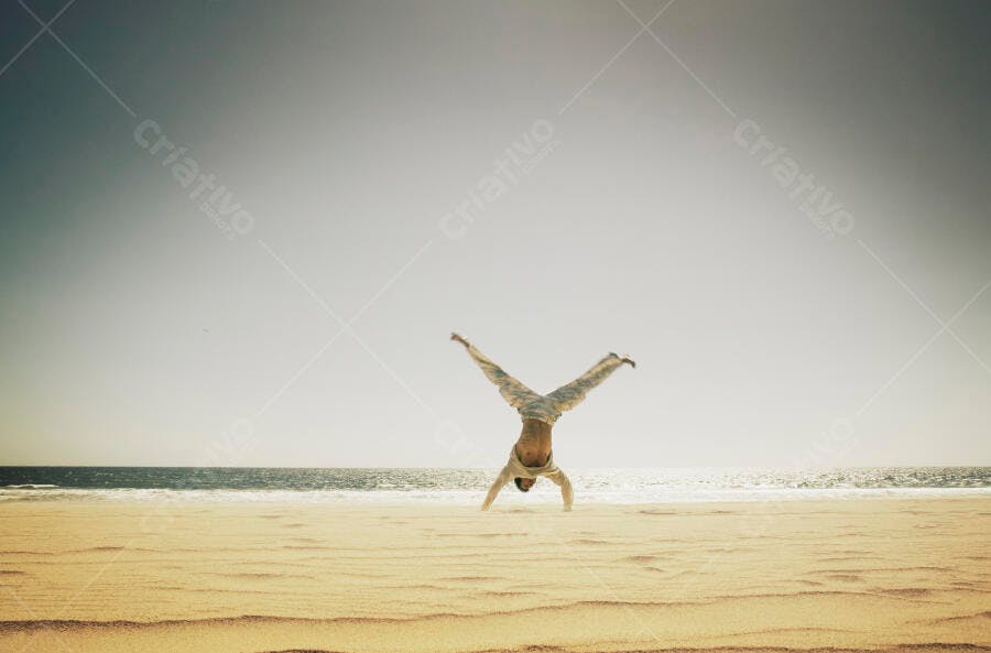 Homem fazendo cambalhota na praia