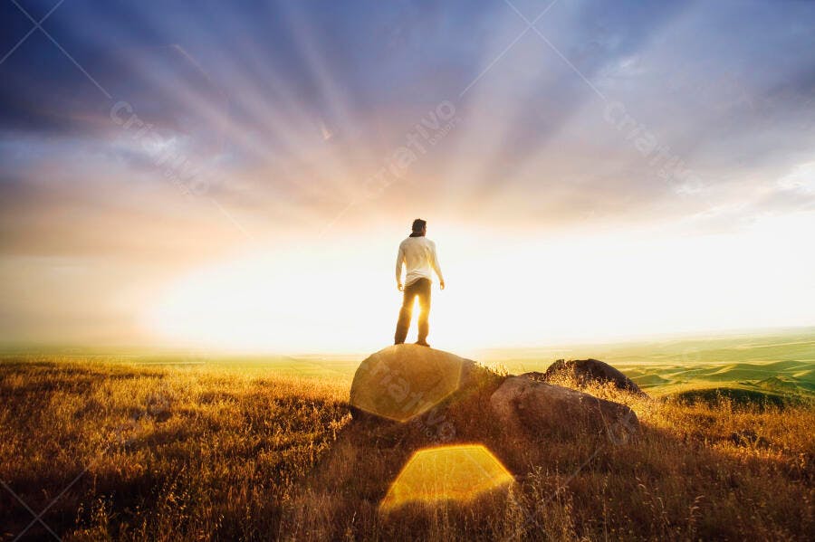 Homem contemplando pôr do sol em campo
