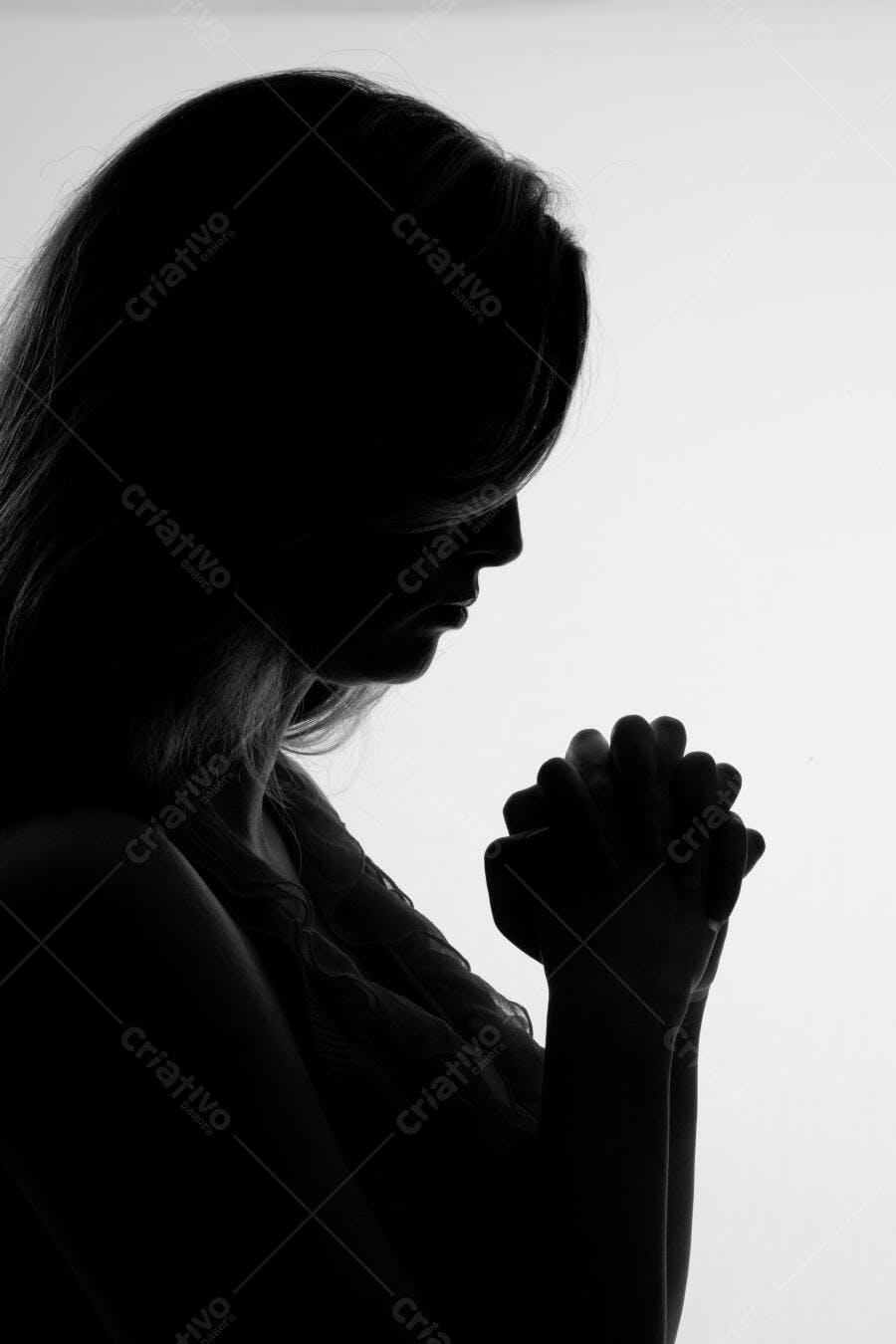 Silhueta feminina orando em tons de cinza