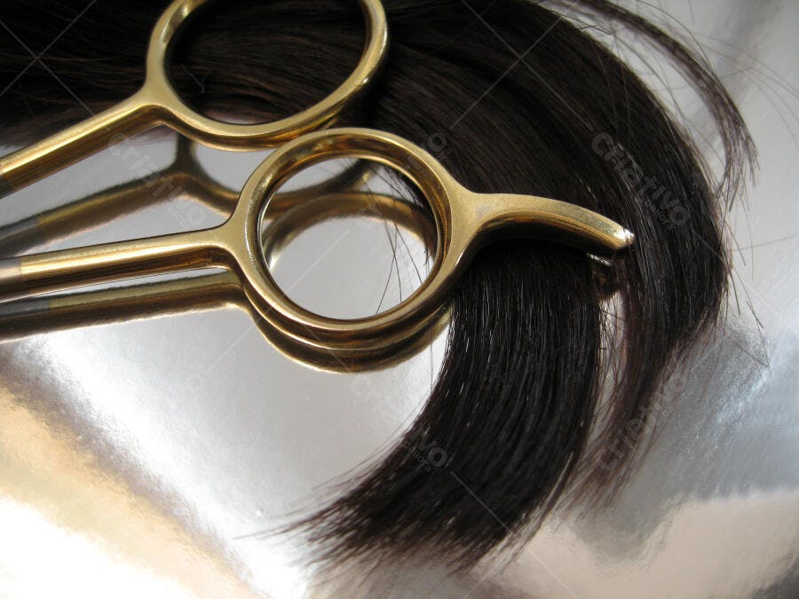 Tesoura dourada e cabelo escuro cortado