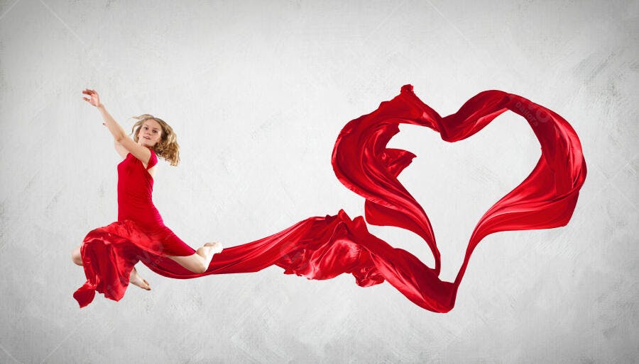Bailarina em vestido vermelho saltando com tecido formando coração