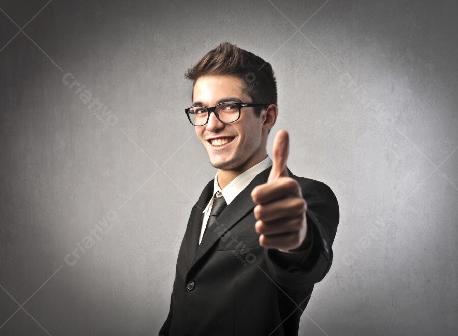 Homem de terno mostrando positivo fundo cinza
