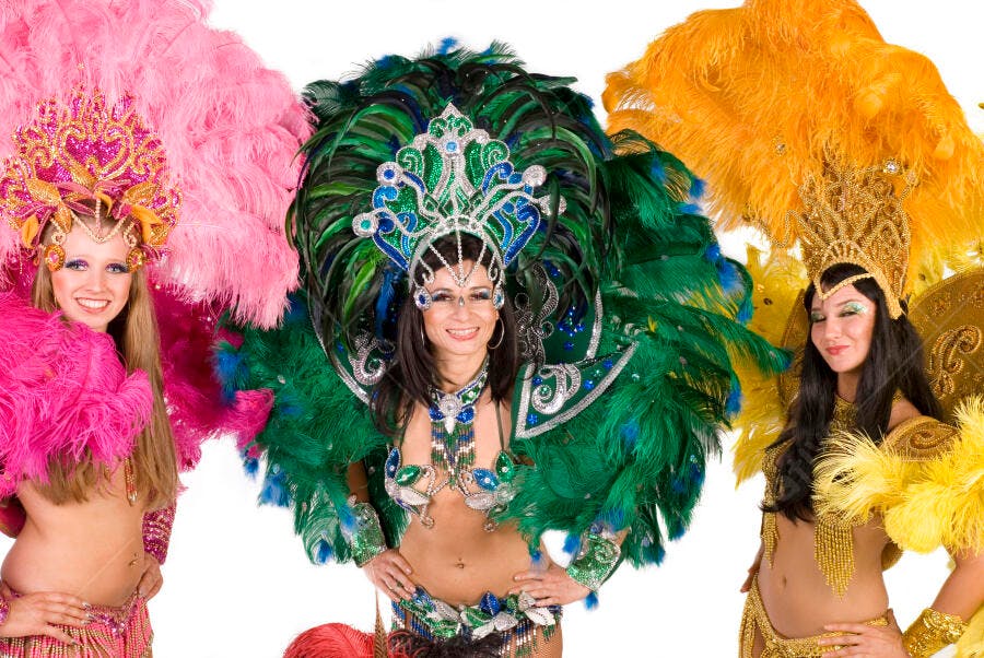Três bailarinas de Carnaval em fantasias vibrantes