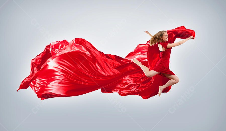 Mulher em vestido vermelho saltando com tecido fluido