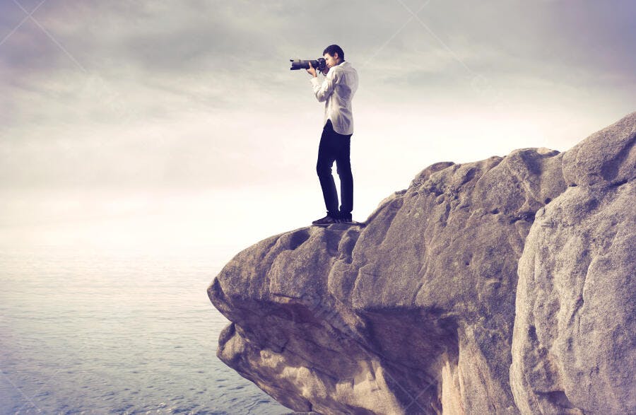 Fotógrafo em penhasco com vista para o mar