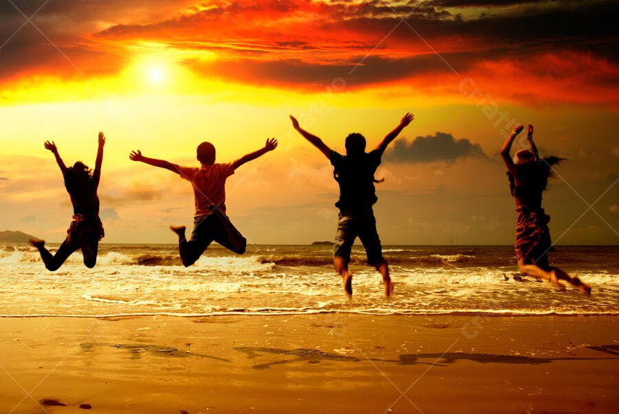 Amigos pulando na praia ao pôr do sol