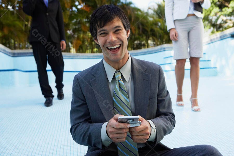 Homem de negócios feliz usando celular perto de piscina