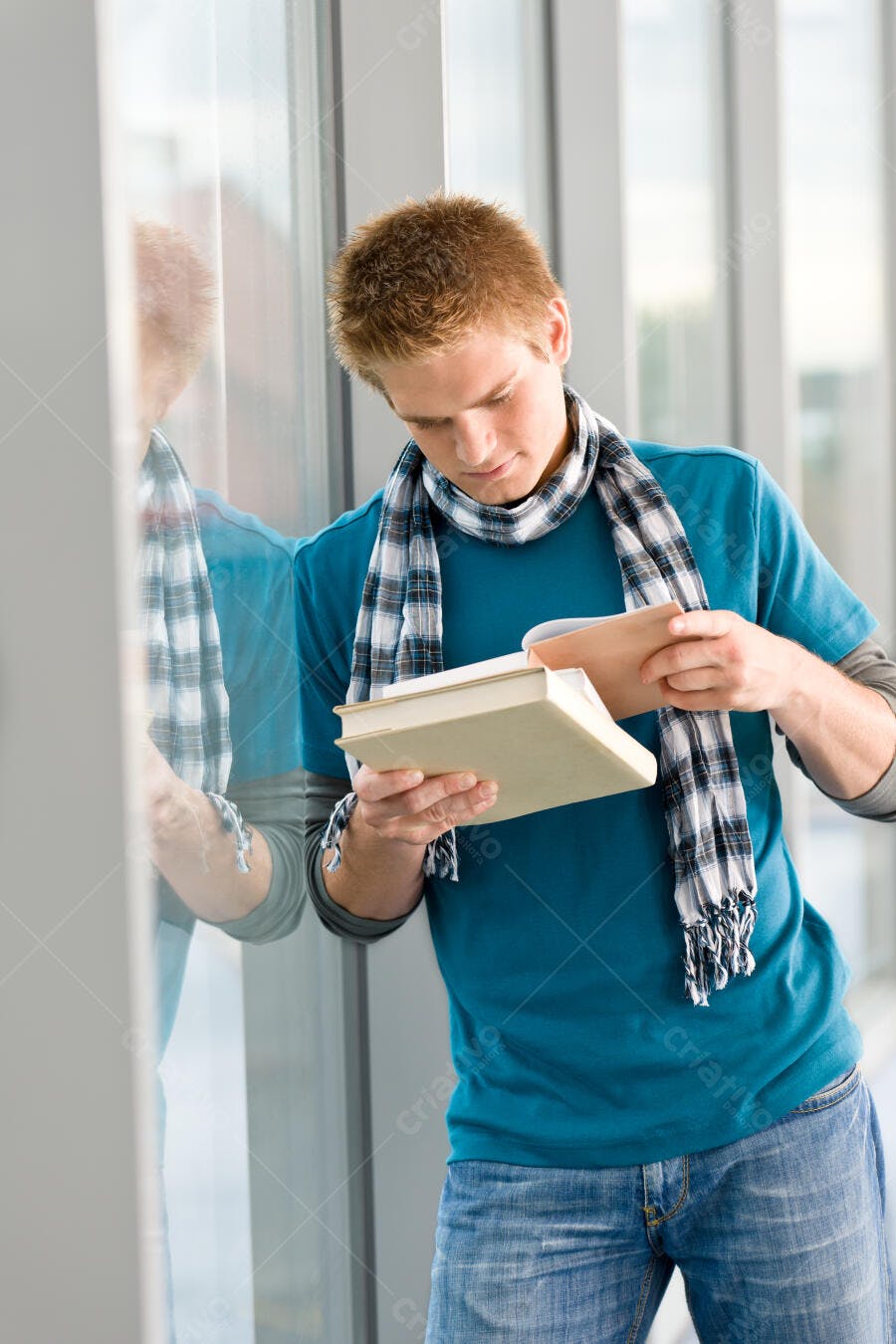Estudante lendo livros perto da janela