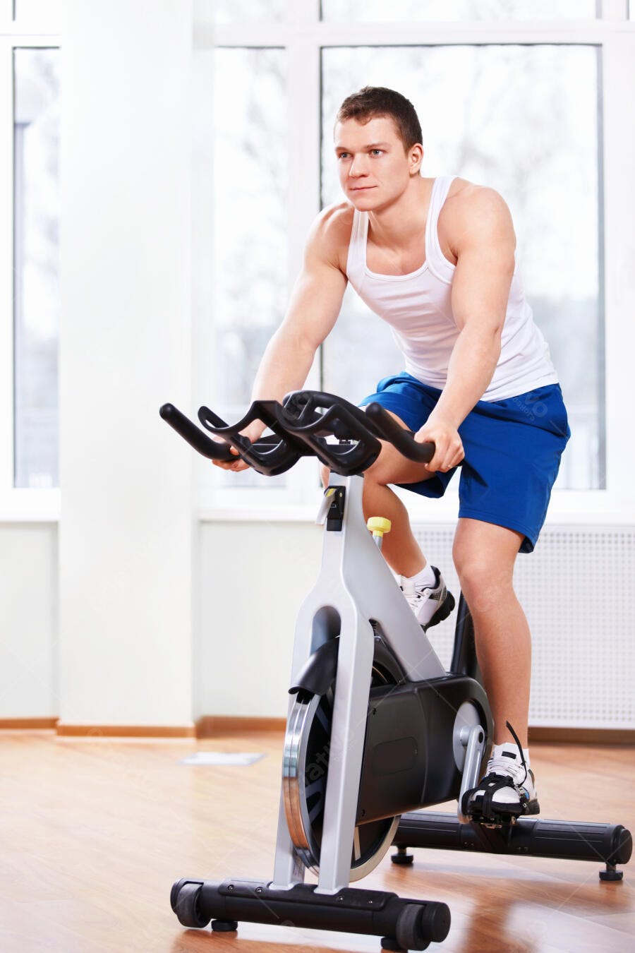 Homem musculoso pedalando bicicleta ergométrica academia