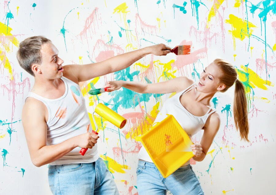 Casal pintando parede com tintas vibrantes